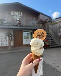 A Bidlea Dairy ice cream cone held up outside the dairy shop