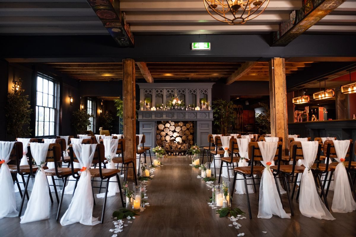 The Main Bar set for a wedding ceremony, with white-draped chairs either side of a candlelit aisle